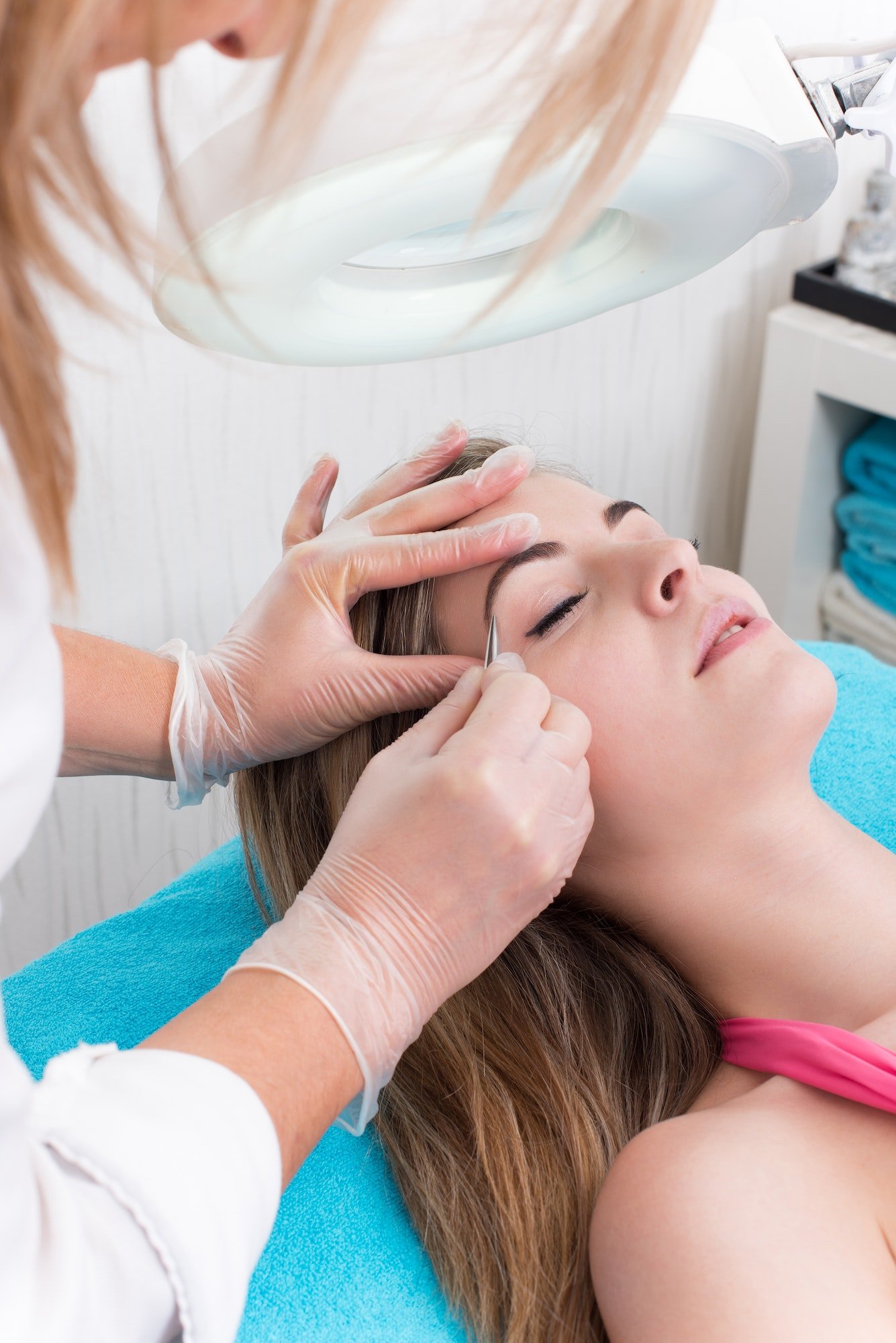 Woman getting tweezing eyebrow Woman getting tweezing eyebrow