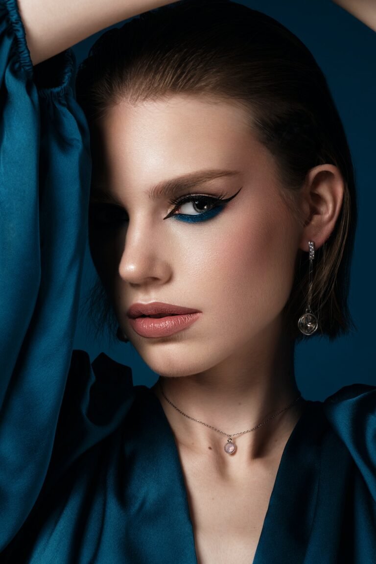 Beautiful woman with blue fabric and classic arrows art make-up. Beauty face.