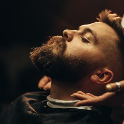 Close shot of a young man beard while he is sitting at a barbershop