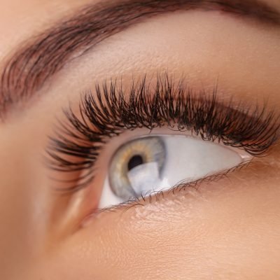 Eyelash Extension Procedure. Woman Eye with Long Eyelashes. Close up, selective focus