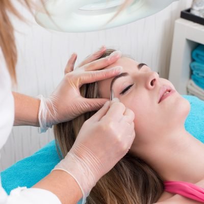 Woman getting tweezing eyebrow